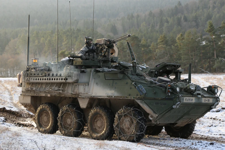 a tank with multiple guns on it driving through the snow