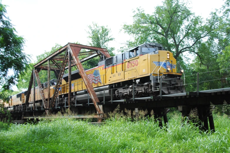 a yellow train traveling through lush green countryside