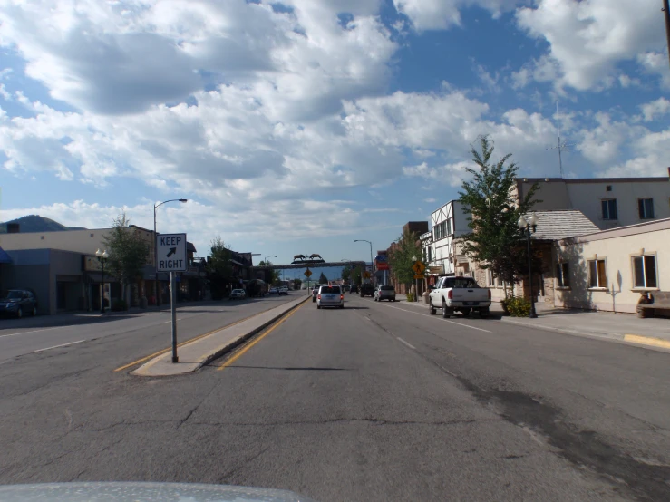 an empty street is lined with shops and a few cars