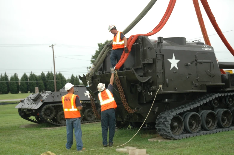 two men in vests and safety jackets with equipment on top of it