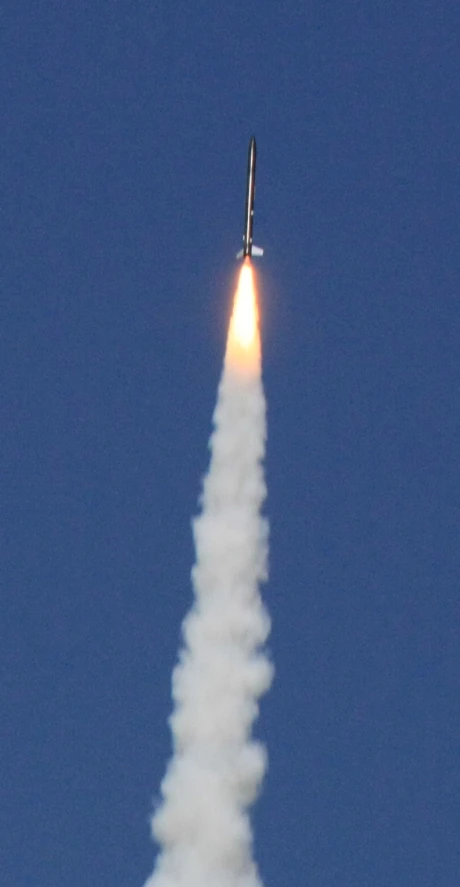 a jet flies in the air with a cloud of smoke