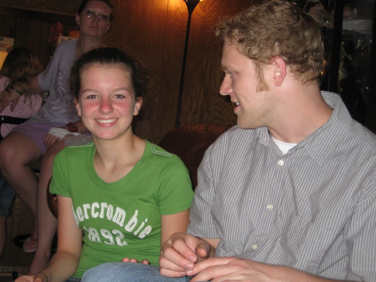 two people sitting down with other people in the background