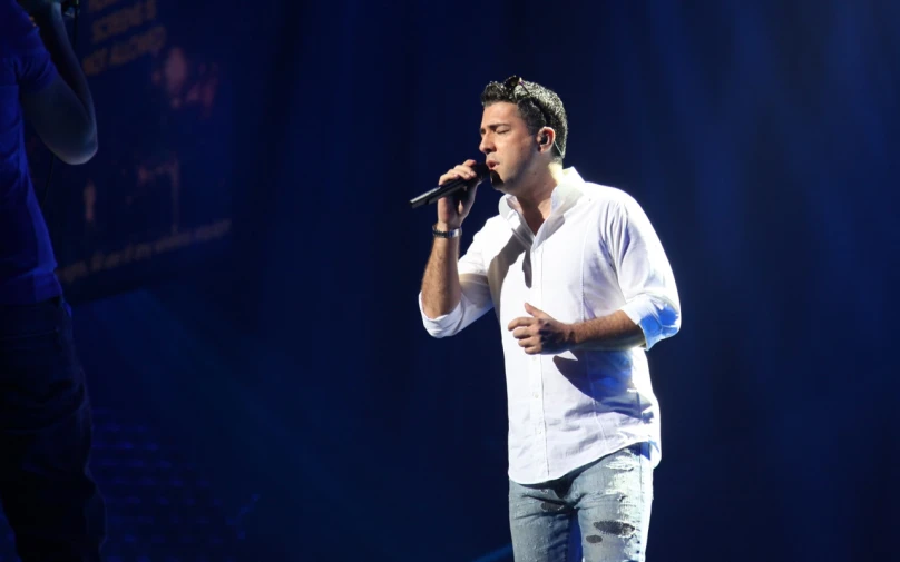 a male in a white shirt and a microphone