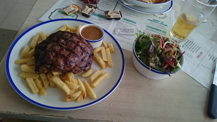 a steak served with fries is next to a plate of fries