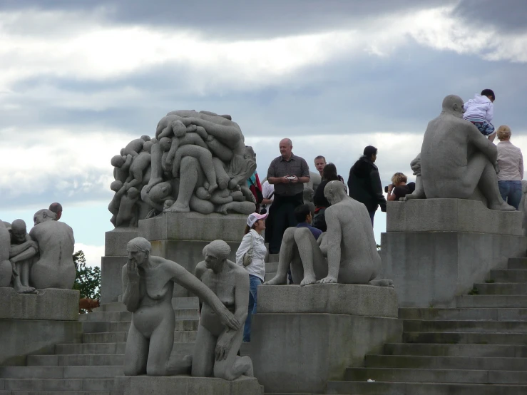 a group of people gather around cement sculptures