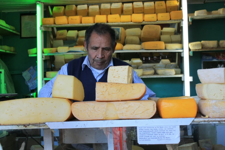 man standing in a market looking over cheese