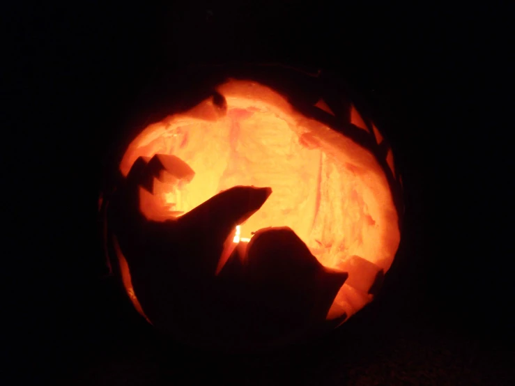 a person carved from a pumpkin sitting in the dark