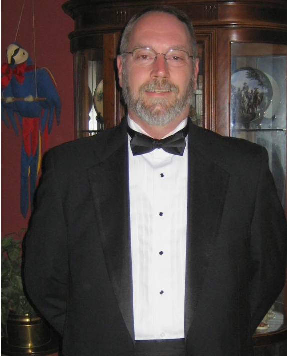 a man is wearing a tuxedo while standing