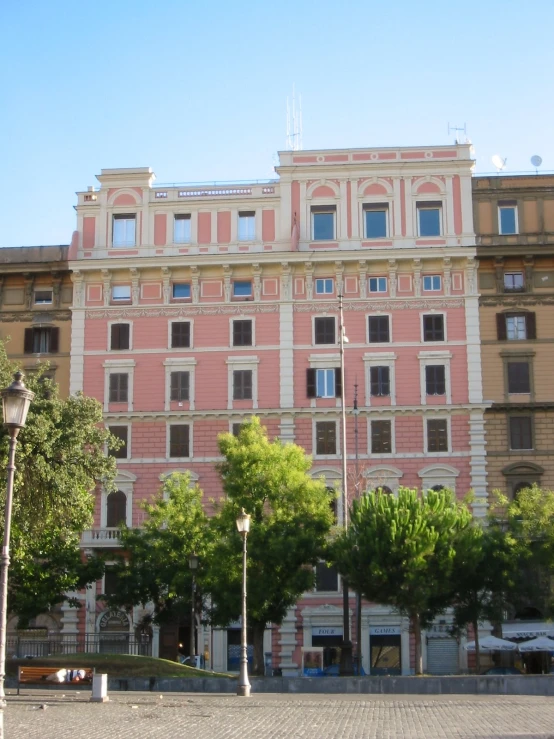 a building with many windows and trees on the sidewalk