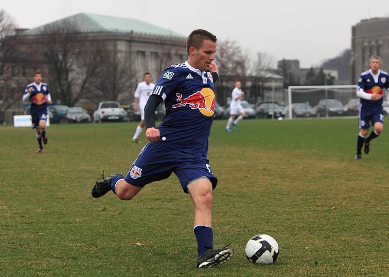 a young man kicking a soccer ball on top of a field