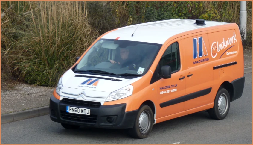 a person in an orange van drives down the street