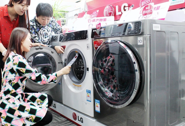 two girls and a woman loading a washing machine