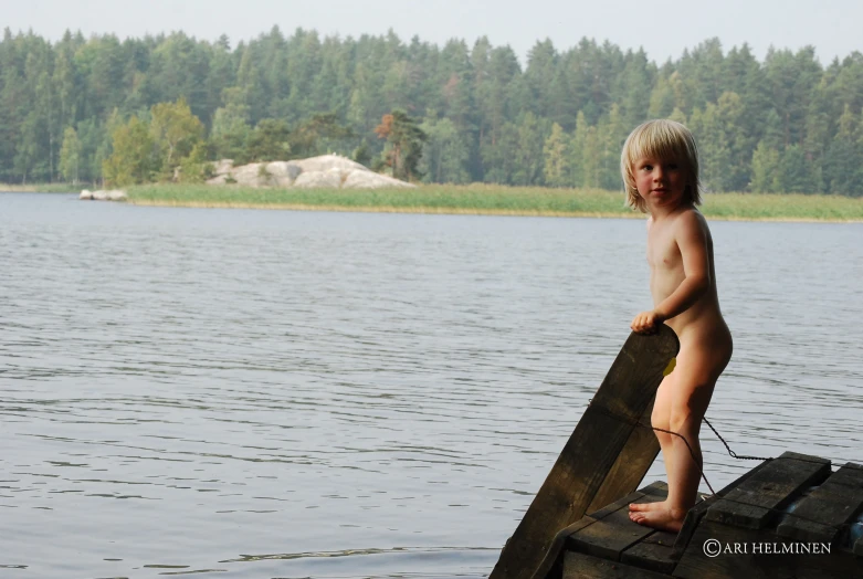 a  boy standing on a dock by a body of water