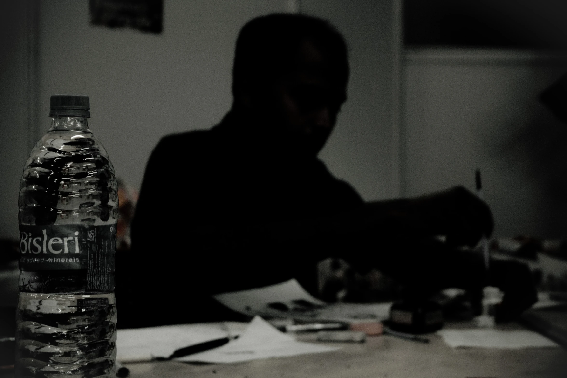 man sits at table with partially finished water bottles