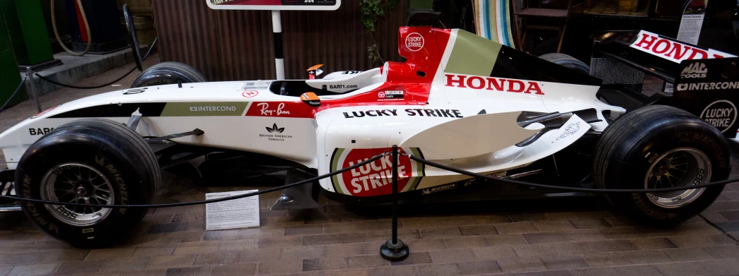 a race car parked on a wooden floor near a sign