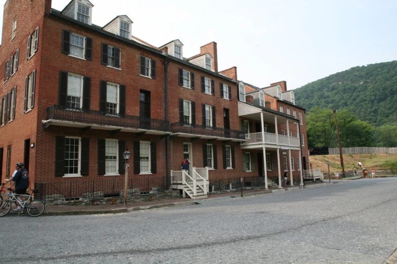 an older - fashioned red brick building is next to two bicycles