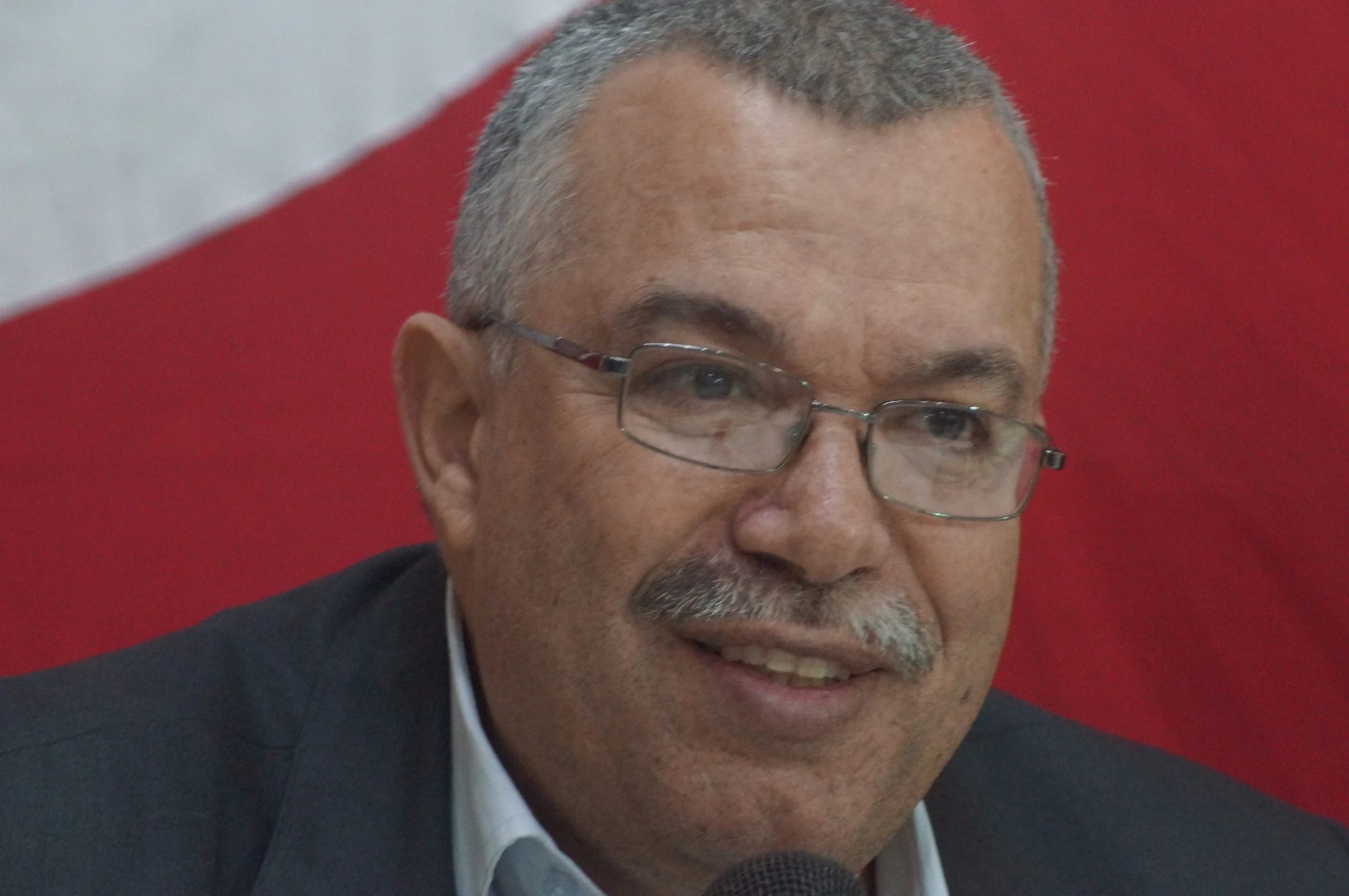 a close up of a person wearing glasses and holding a microphone