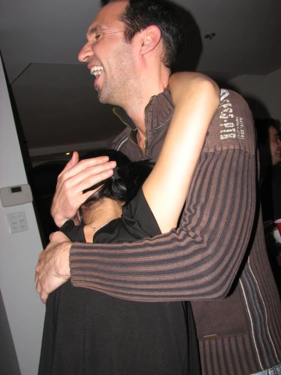 a man hugging a girl with a funny look on her face