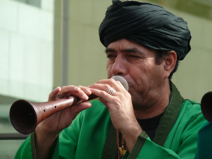 a man wearing a black turban and playing a metal pipe