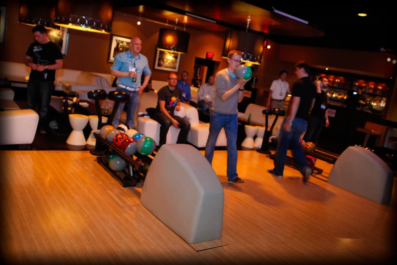 four men are bowling at the bowling alley with two bowling balls