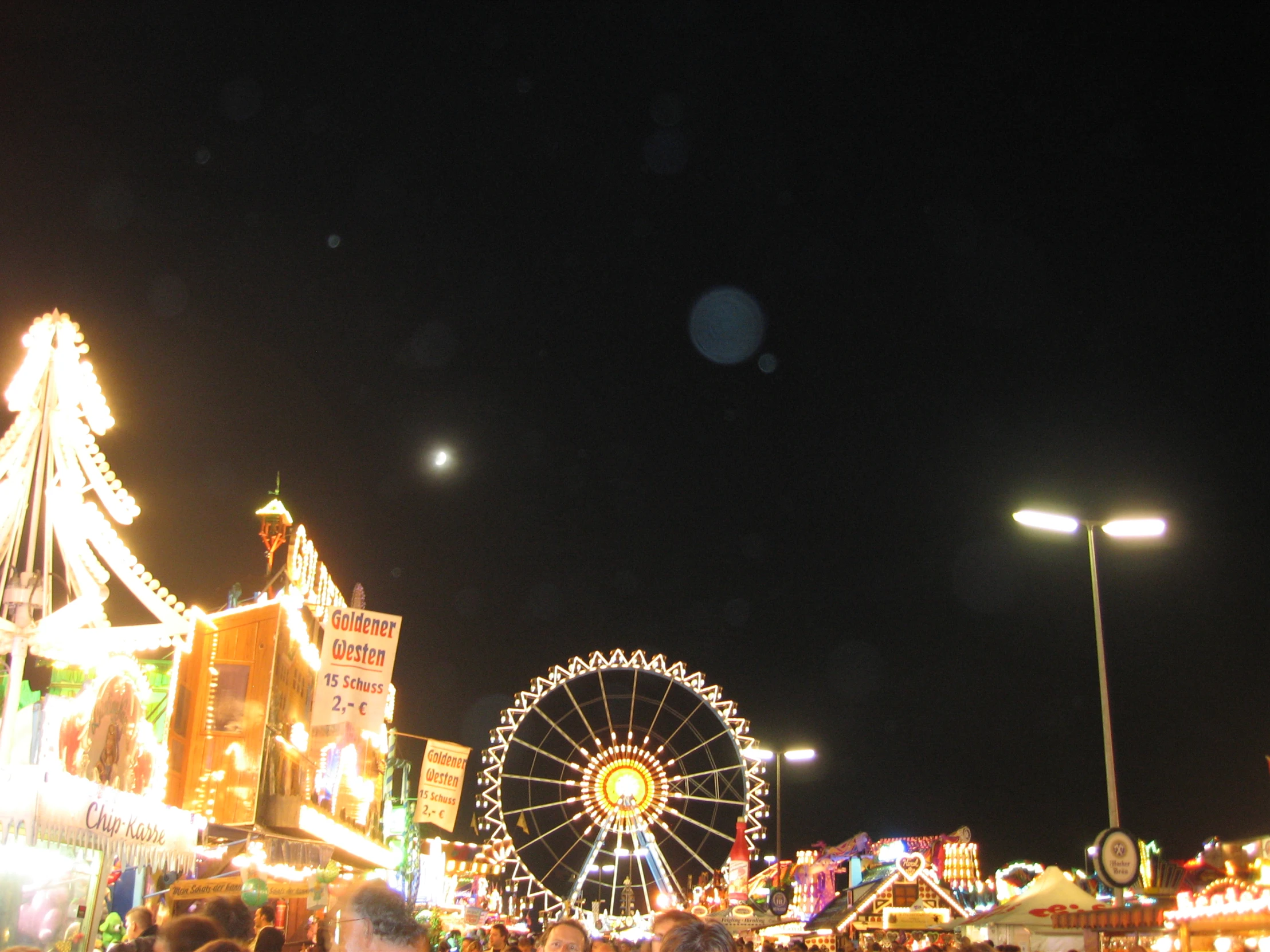 a crowd of people walking around a fair at night