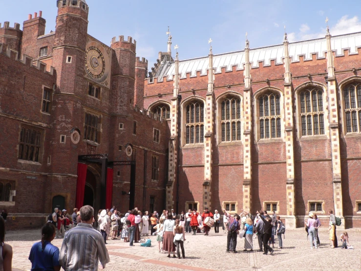 many people standing outside of an old castle like building