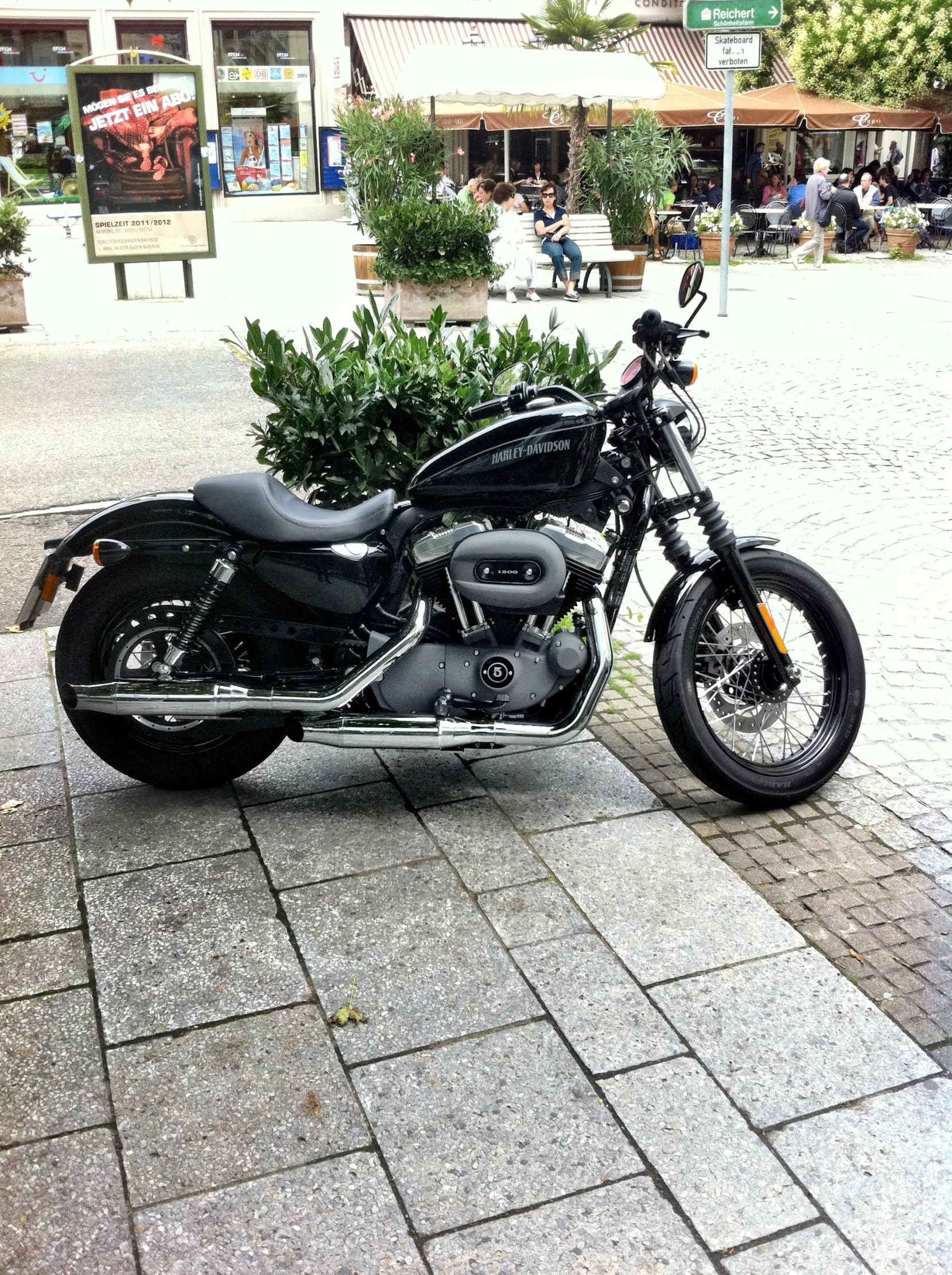 a motorcycle is parked on the sidewalk near some bushes