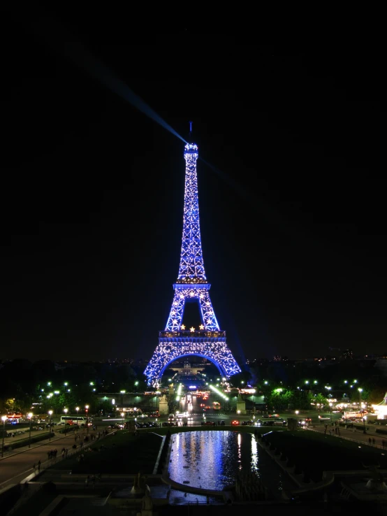 the eiffel tower illuminated at night, seen from across a river