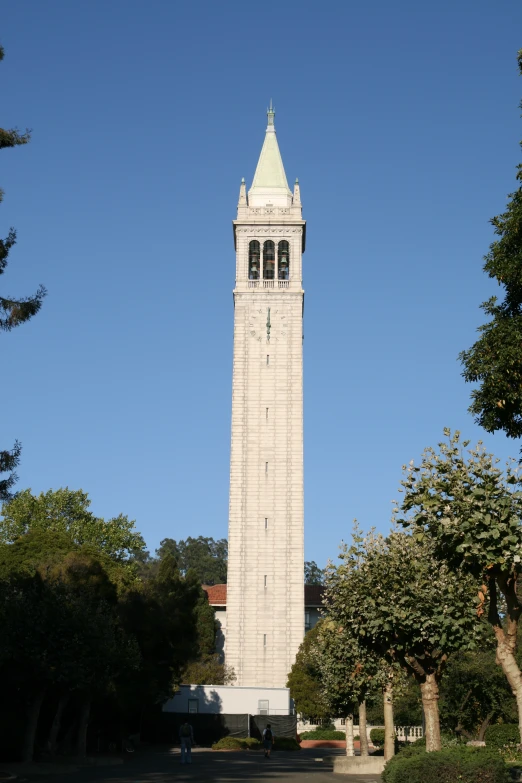 a large stone clock tower with trees and a road below