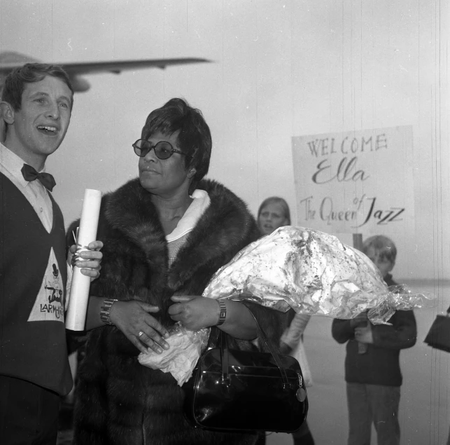 a man holding a bouquet and a woman in front of a wall