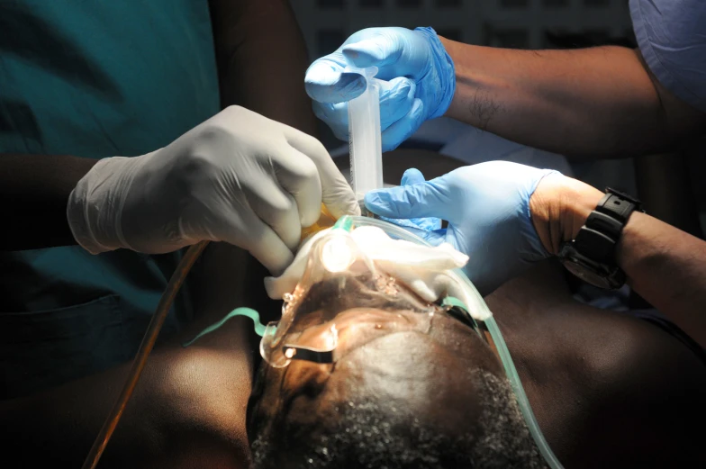 someone wearing gloves with one hand while operating an iv