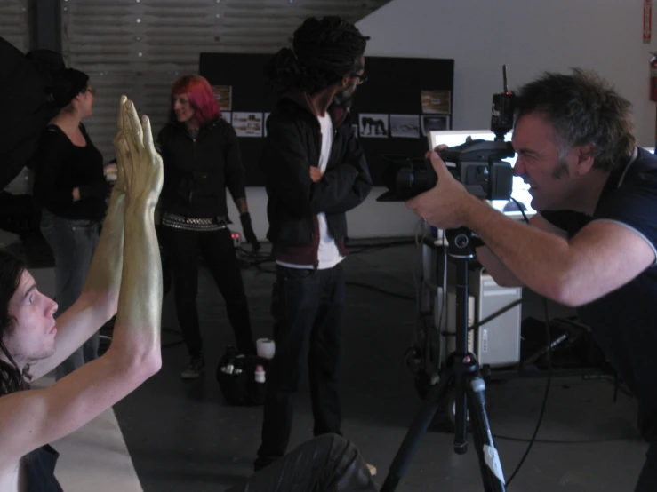 people standing around a woman in a black shirt filming