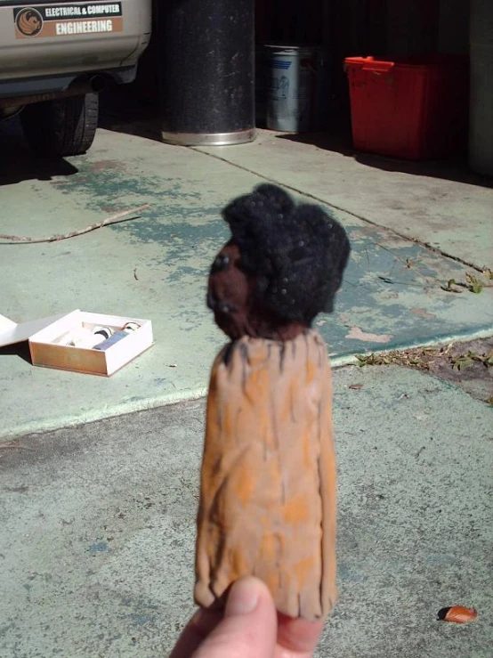 a fake child doll with a cigarette next to a white object