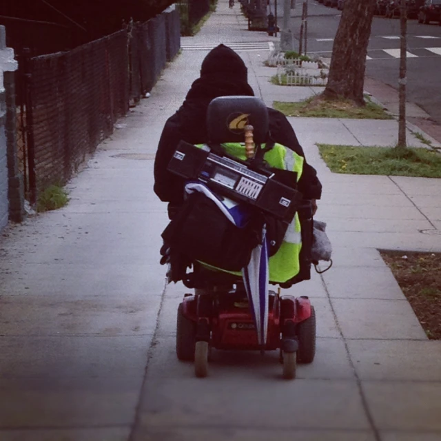 a young person with an extra large back pack on their arm in a wheel chair