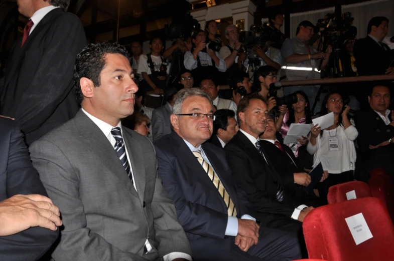 a number of men in suits sitting and watching soing