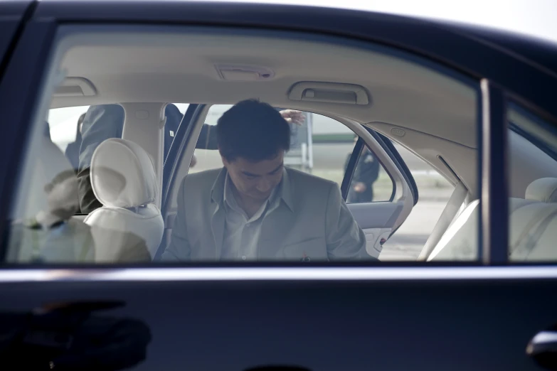 a man looking at his cell phone in the passenger seat of a car