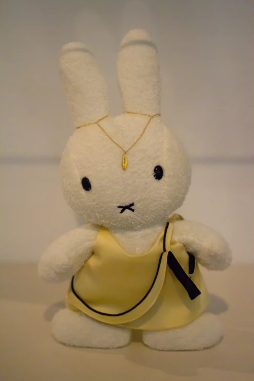 a white stuffed rabbit wearing a yellow dress