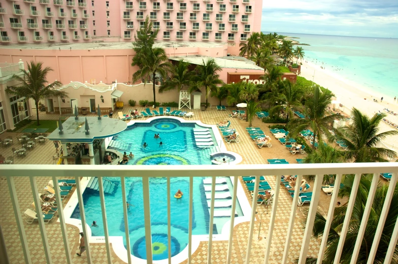 a pool with chairs and beachfront buildings in the background