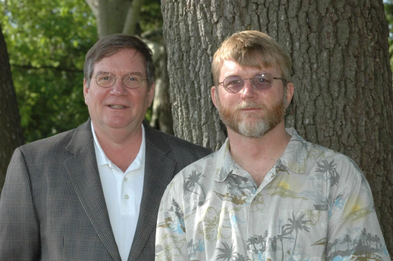 two men stand side by side next to trees