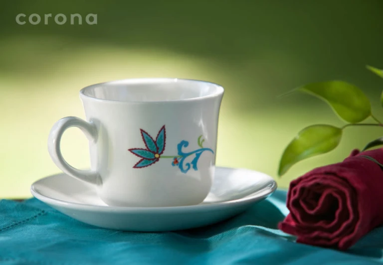 a close up of a cup on a plate near a flower