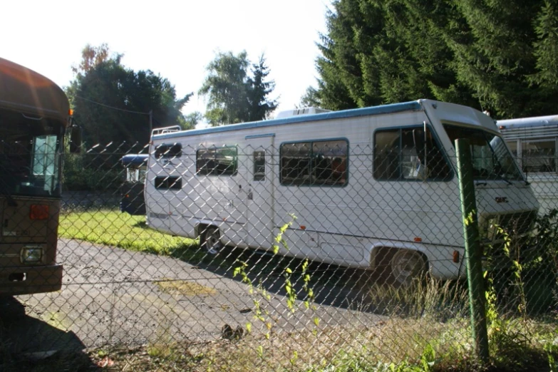 two van trailers sit behind a fence, and the one behind them looks like it has been vandalized