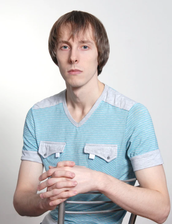 a man sitting on a chair in front of a white wall