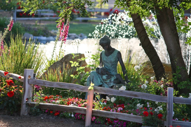 a statue sits on the edge of a garden