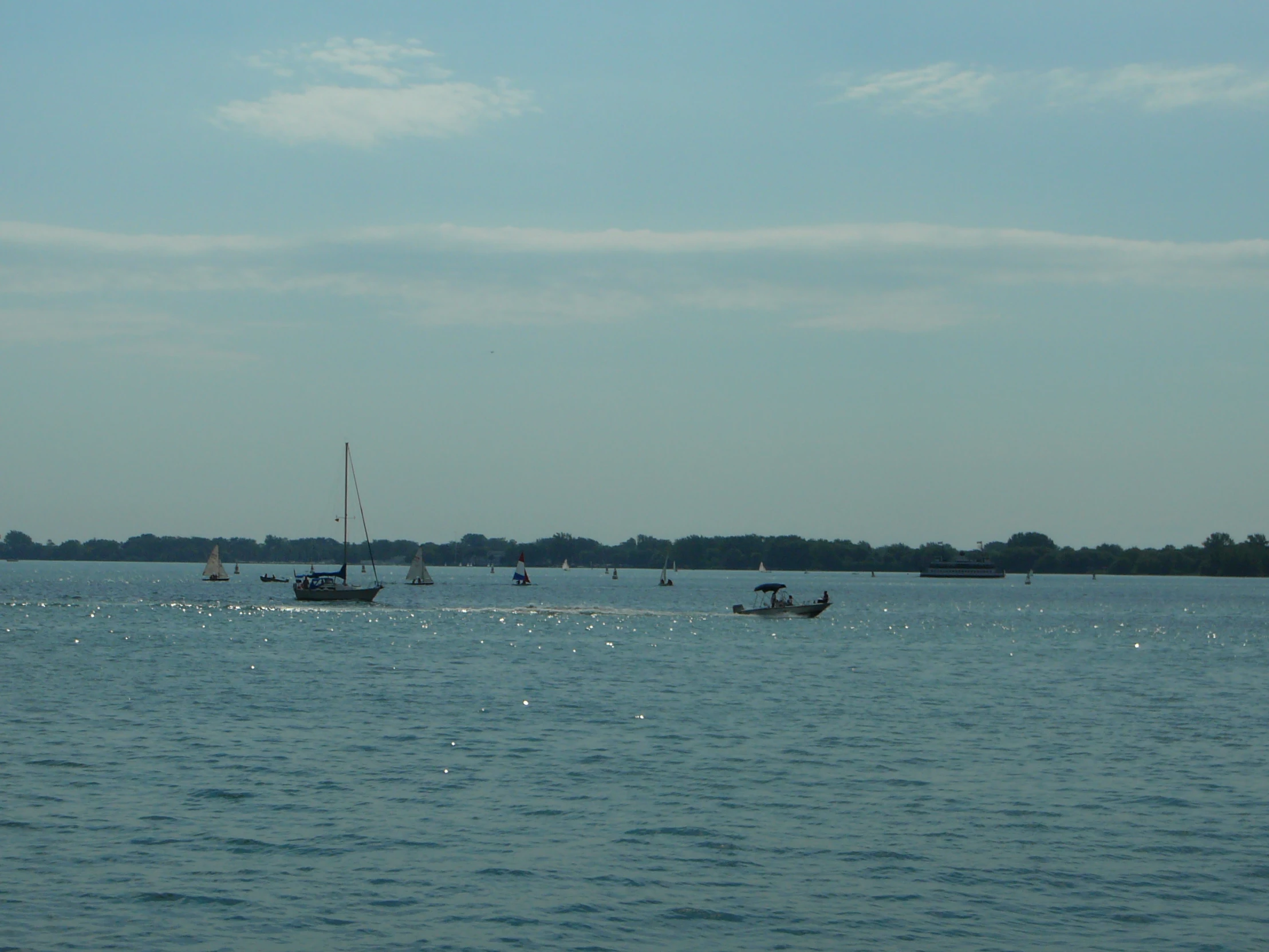 some boats are floating in the water by a shoreline