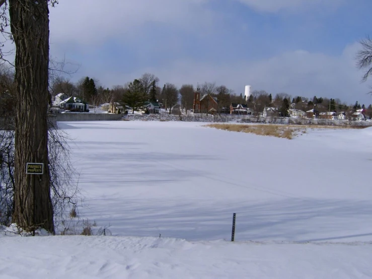 a snowy field with snow on it and buildings in the distance