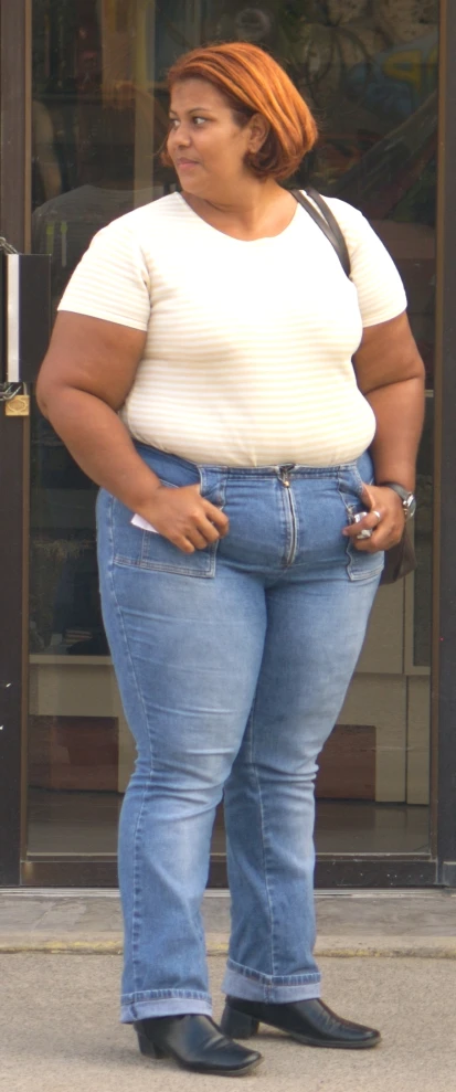 a woman in high rise jeans standing in front of a store window