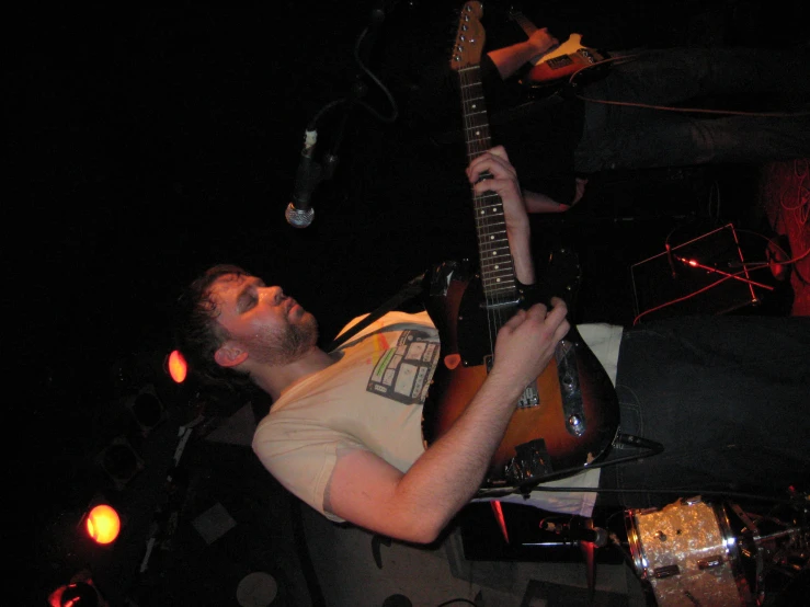 a young man playing an electric guitar on stage