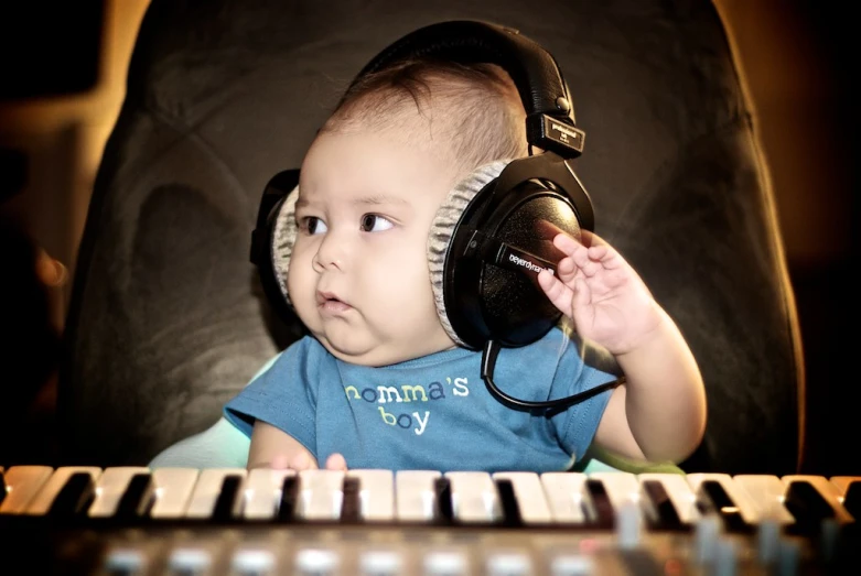 a baby boy sits on a couch wearing headphones