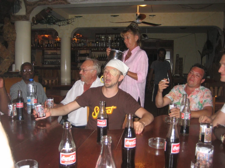 a number of people in a bar, one with a hat on his head