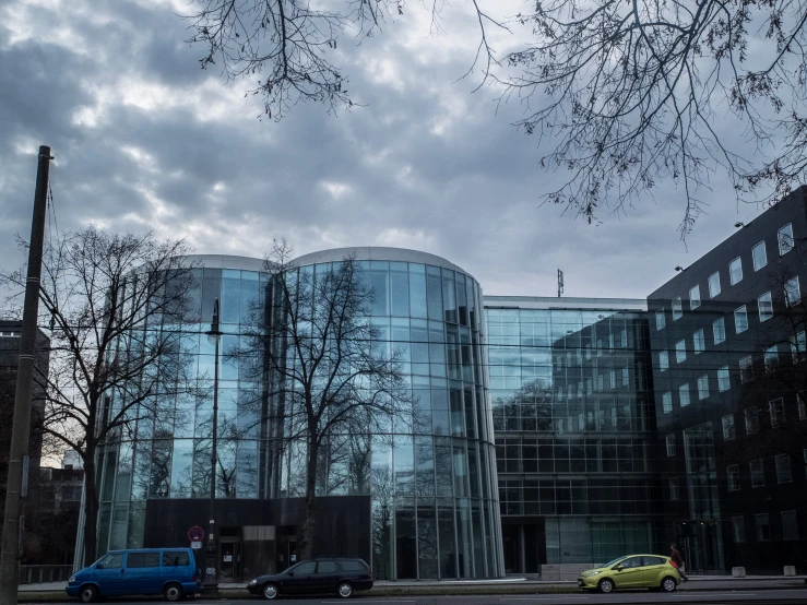 three vehicles parked outside a very large building with glass windows